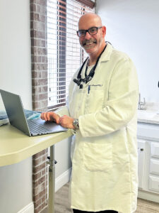Doctor Brunner, smiling and working on a laptop computer in the dental office