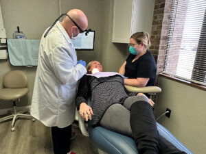 Doctor Brunner and a dental assistant attending to a patient in the exam chair