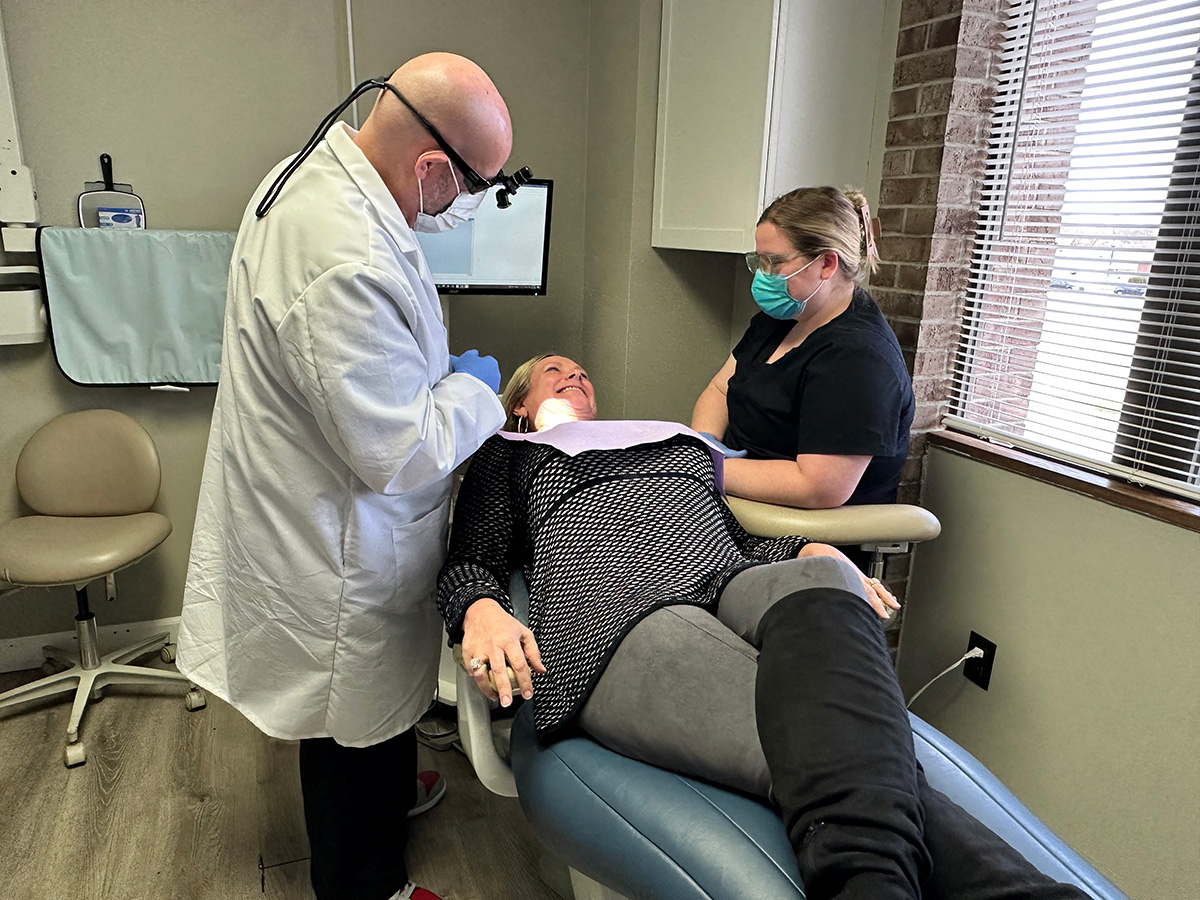 Doctor Brunner and a dental assistant attending to a patient in the exam chair